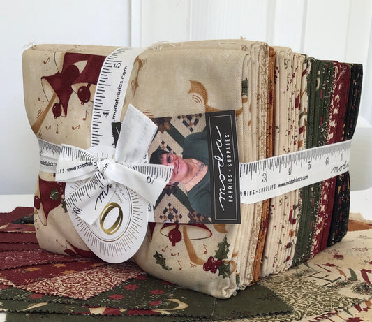 A bundle of fat quarters with Christmas-themed prints, tied together with a white ribbon and a measuring tape.